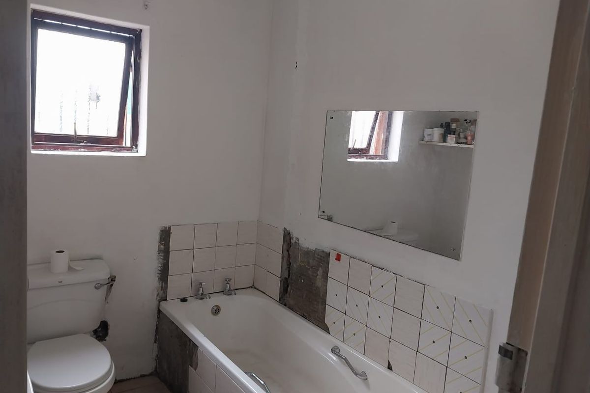 A bathroom featuring a bathtub and toilet, currently requiring completion of wall tiling and plastering work to improve the overall finish.