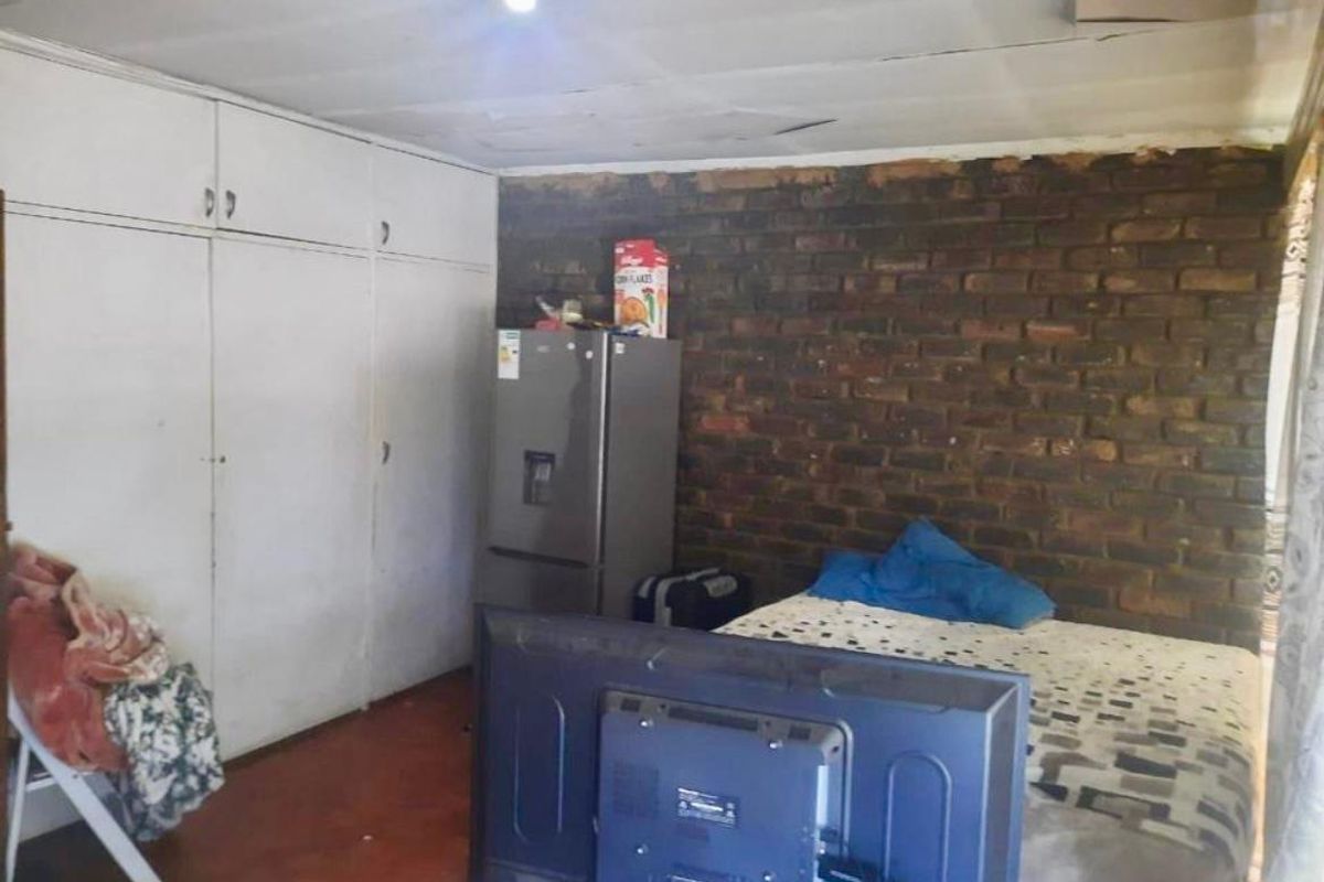 Bedroom featuring built-in cupboards and an exposed brick feature wall, requiring ceiling repairs and general refurbishment to improve the living space.