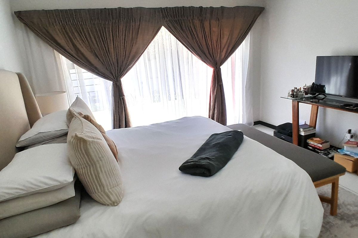 A well-maintained bedroom featuring recessed downlighting, cove cornicing, and a large sliding glass door providing natural light.