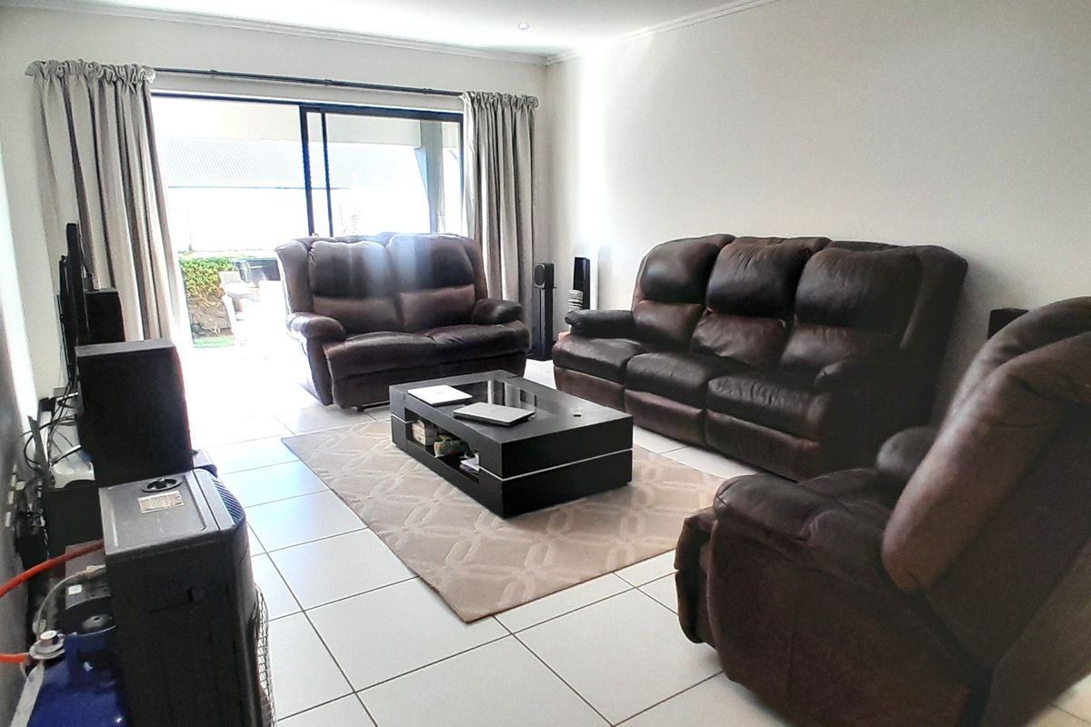 Spacious living room featuring neutral tiled flooring, recessed lighting, and large sliding glass doors providing direct access to the outdoor patio area.
