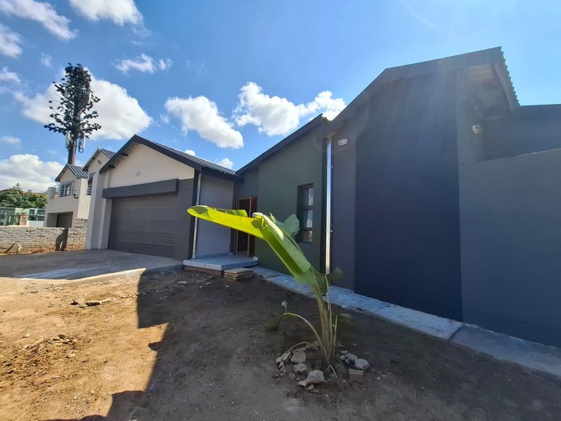 Modern front elevation of a house featuring a double garage, contemporary dark exterior paint, and an unfinished garden area.