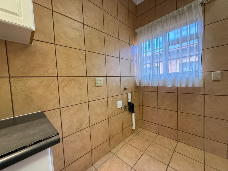 A functional laundry area featuring tiled walls and flooring, with dedicated plumbing and electrical connections for appliances.