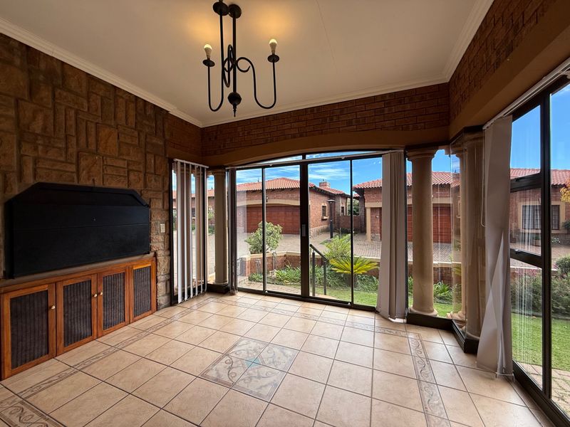 A spacious enclosed patio featuring tiled floors, a stone feature wall, built-in cabinetry, and large sliding glass doors overlooking the complex exterior.