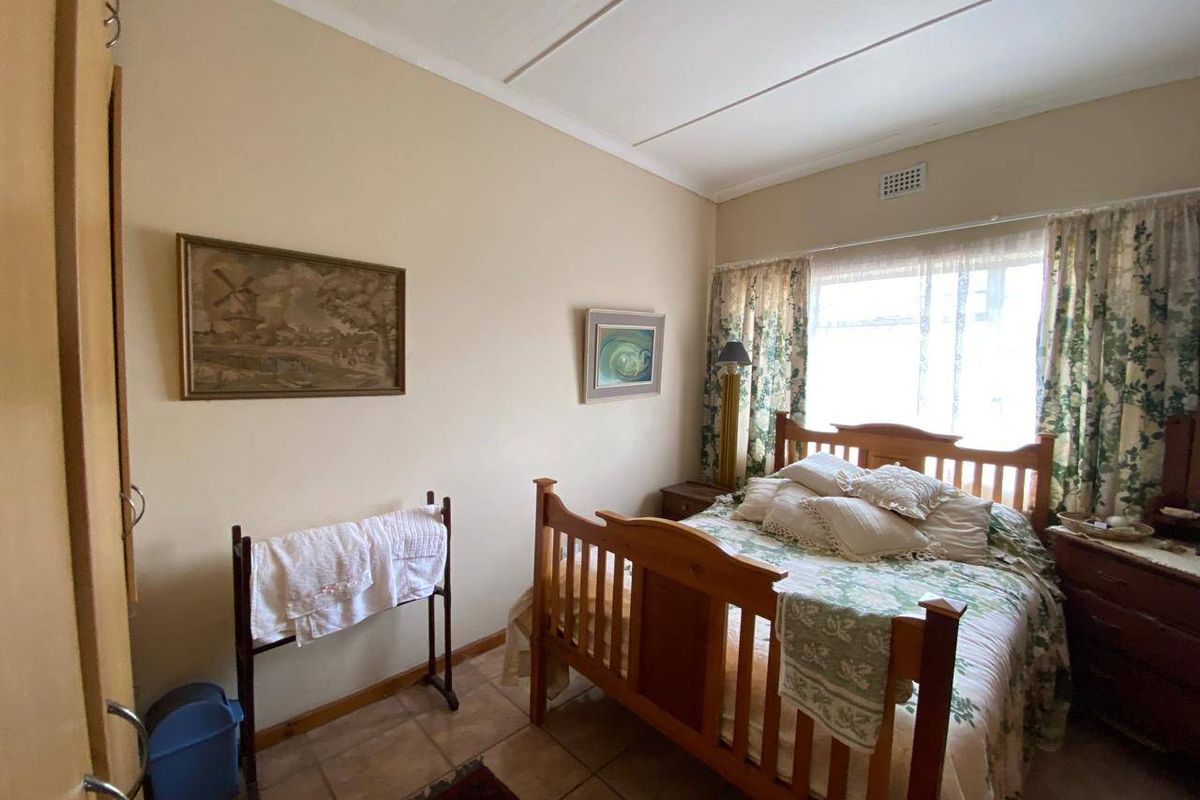 A functional bedroom featuring tiled flooring, a built-in cupboard, and a ceiling vent, offering a neutral base for potential updates.