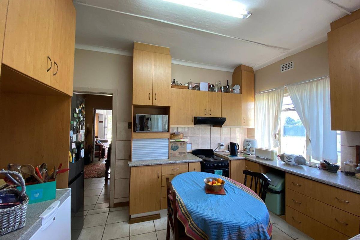 A functional kitchen featuring laminate cabinetry, tiled backsplash, and ceramic flooring, offering a dated but practical layout with built-in cooking appliances.