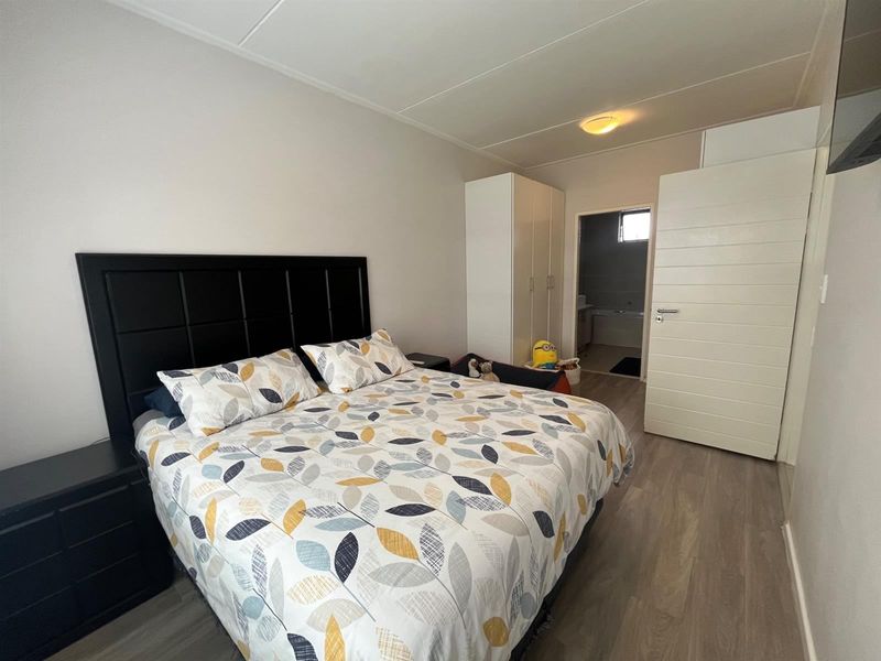 A well-maintained bedroom featuring laminate flooring, a built-in wardrobe, and direct access to an en-suite bathroom.