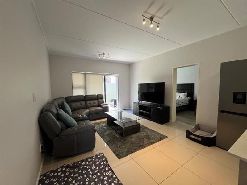 Open-plan living area featuring large format floor tiles, neutral wall finishes, and a sliding door providing access to an outdoor space.