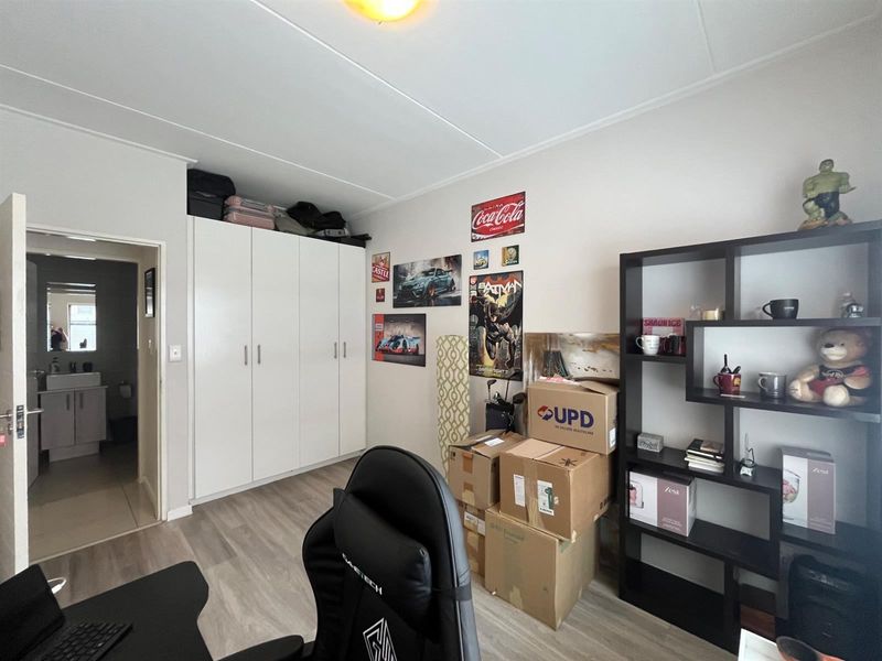 A bedroom featuring built-in cupboards, laminate flooring, and an adjoining bathroom, providing a functional living space.