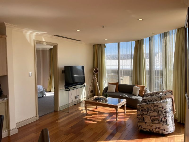 A bright living room featuring polished hardwood flooring, recessed lighting, and expansive floor-to-ceiling windows that provide ample natural light.
