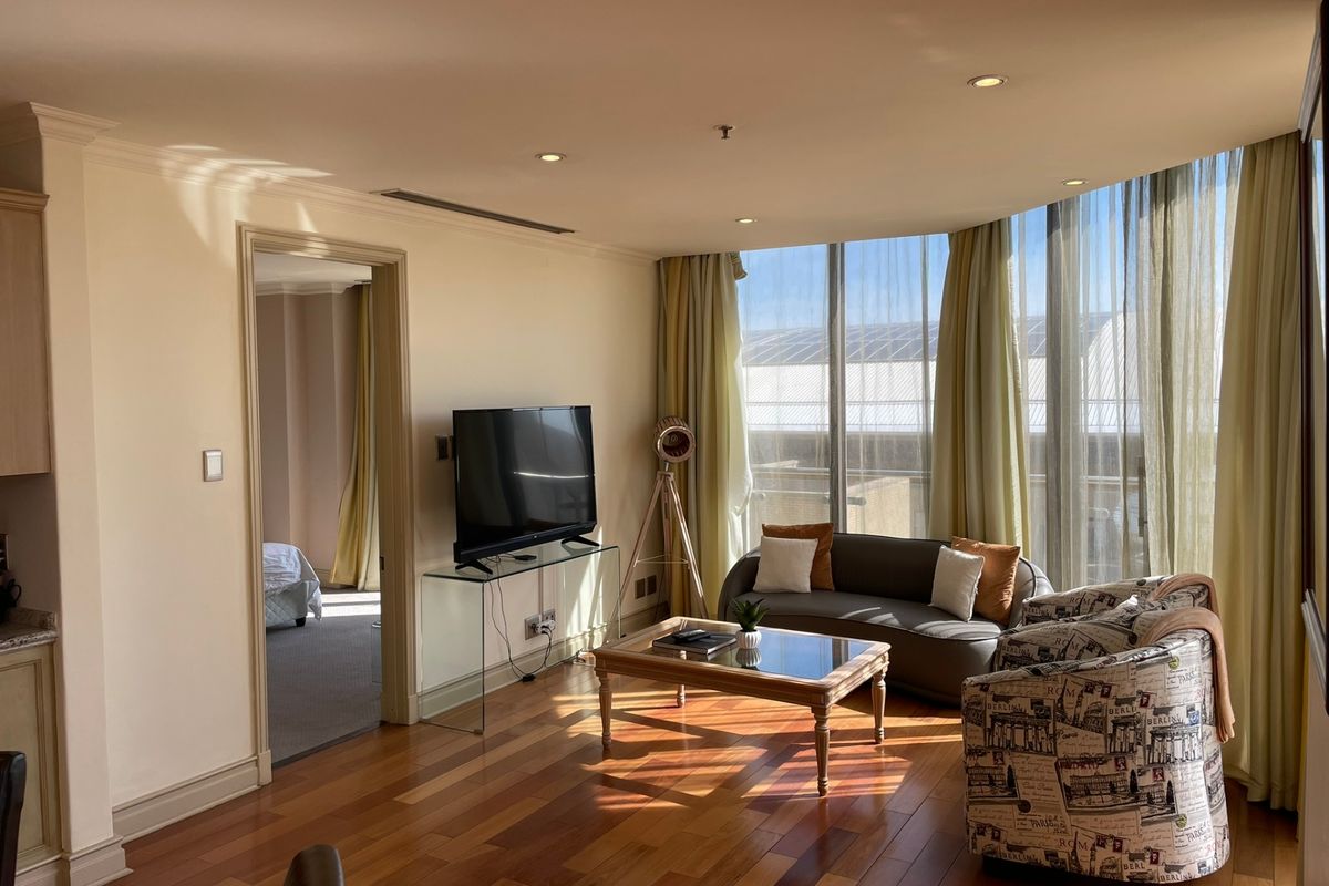 A bright living room featuring polished hardwood flooring, recessed lighting, and expansive floor-to-ceiling windows that provide ample natural light.