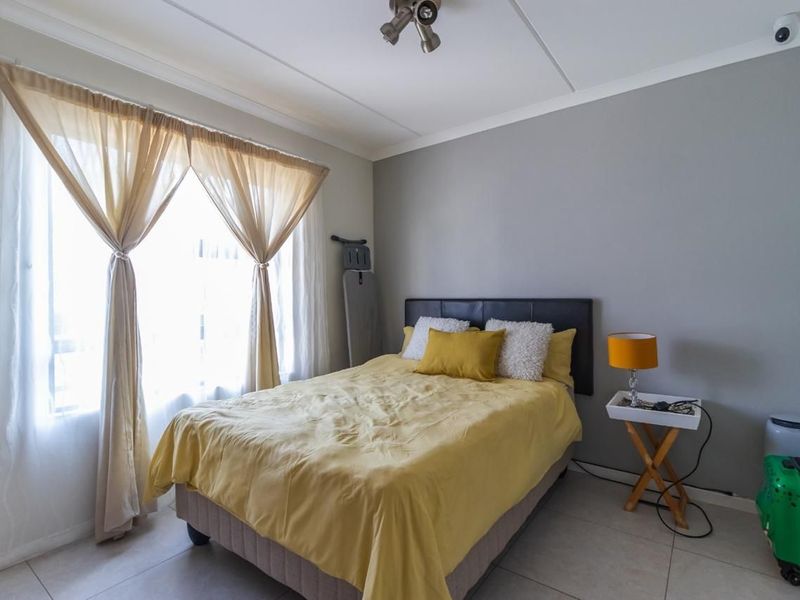 A bedroom featuring tiled flooring, neutral grey walls, and a ceiling-mounted spotlight fixture.
