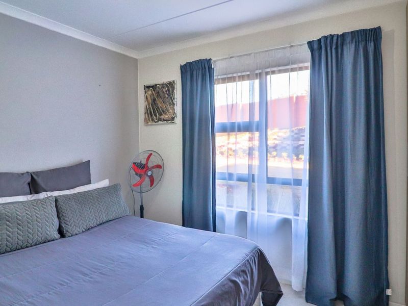 A well-maintained bedroom featuring a built-in wardrobe, neutral wall finishes, and a window with natural light.