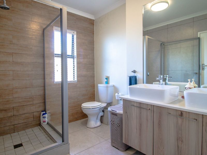 Modern bathroom featuring a walk-in shower with wood-look tiling, a dual vanity with vessel sinks, and contemporary fixtures.