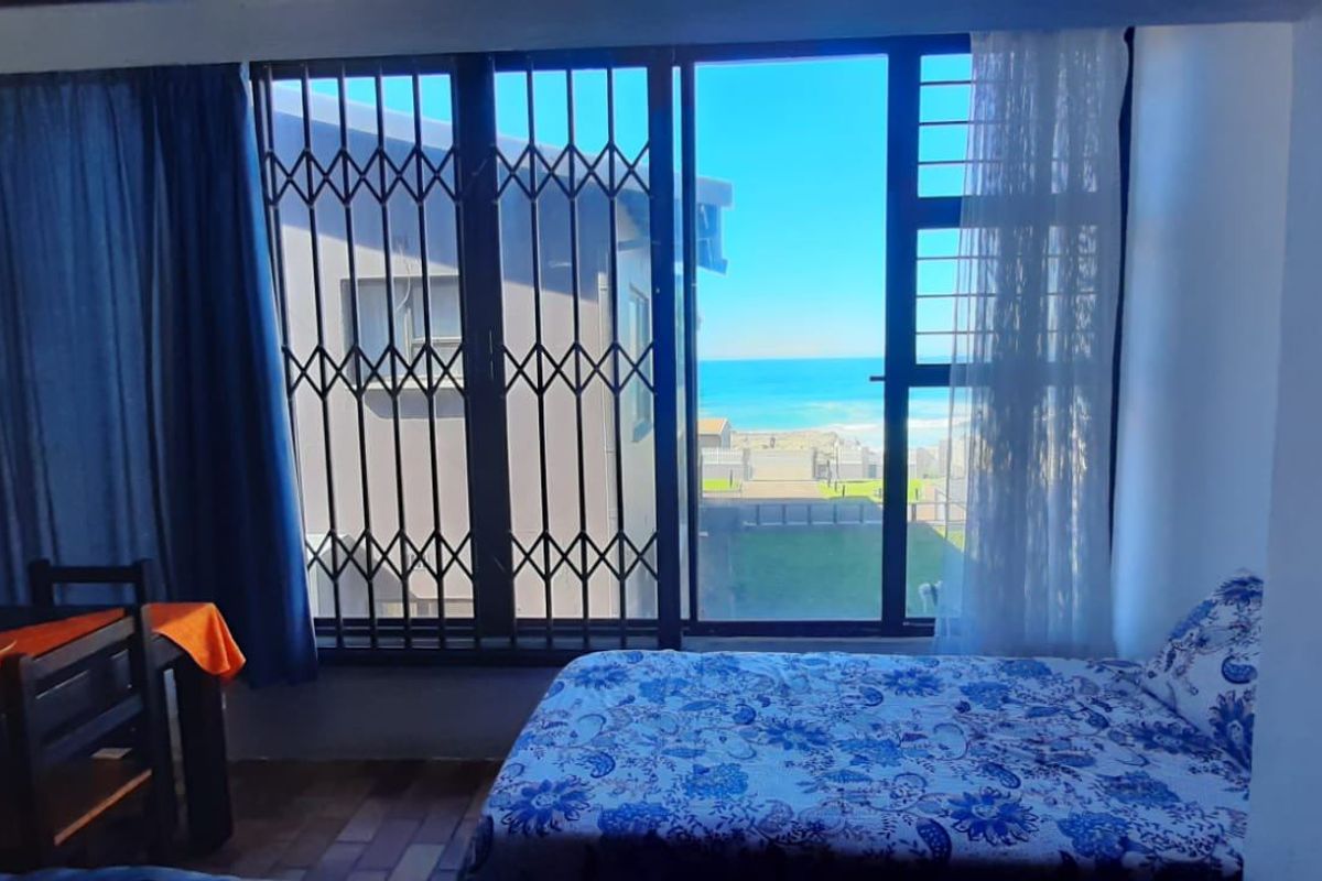Bedroom featuring tiled flooring and a sliding door with a security gate, offering a view of the ocean.