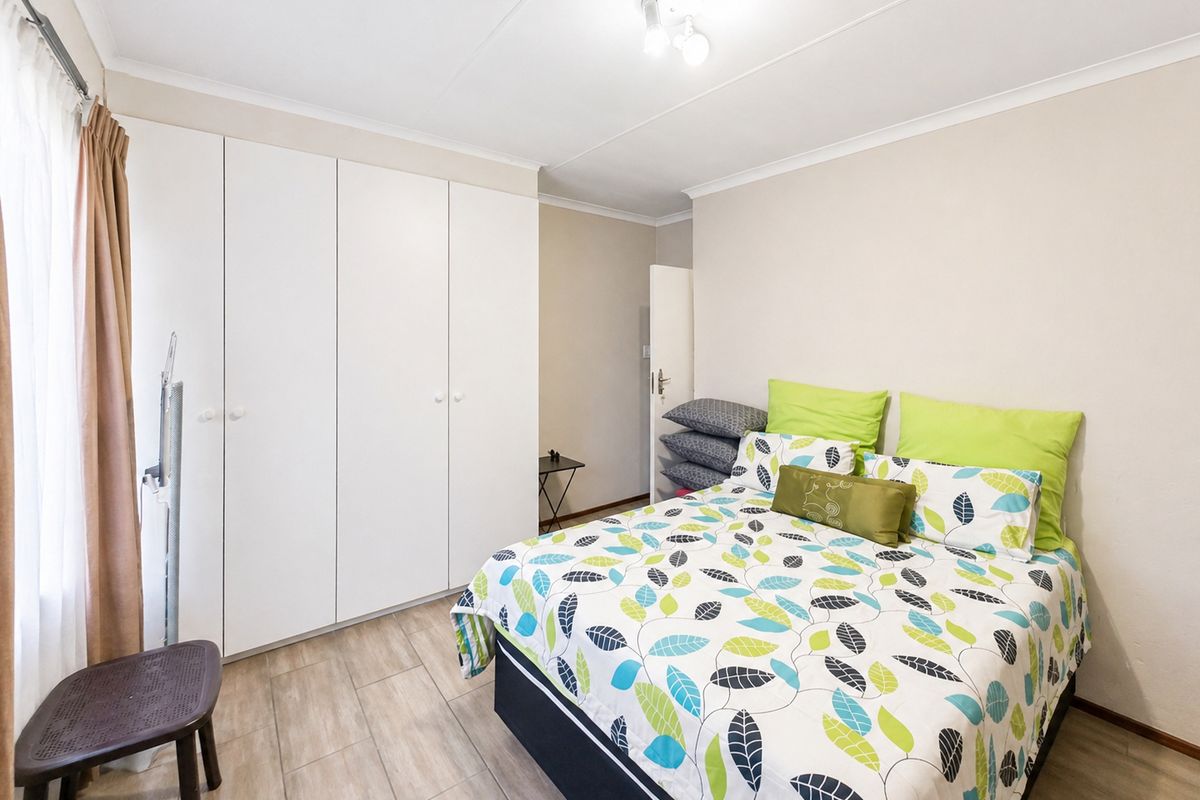 A bedroom featuring built-in floor-to-ceiling wardrobes, tiled flooring, and neutral wall finishes, providing a functional and clean living space.