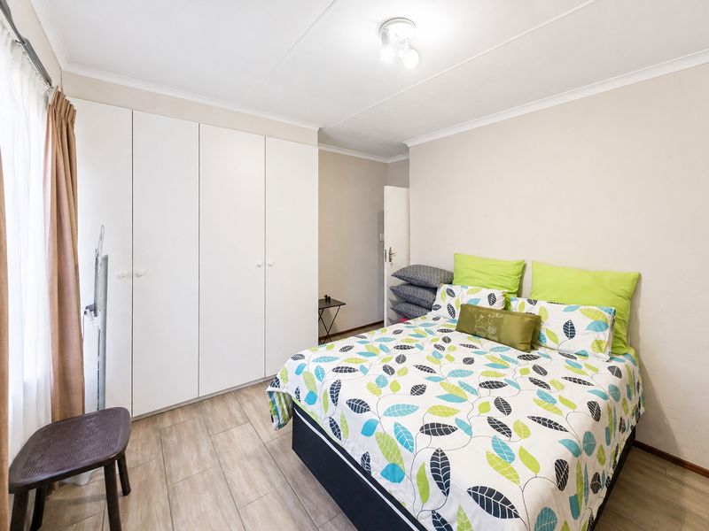 A bedroom featuring built-in floor-to-ceiling wardrobes, tiled flooring, and neutral wall finishes, providing a functional and clean living space.