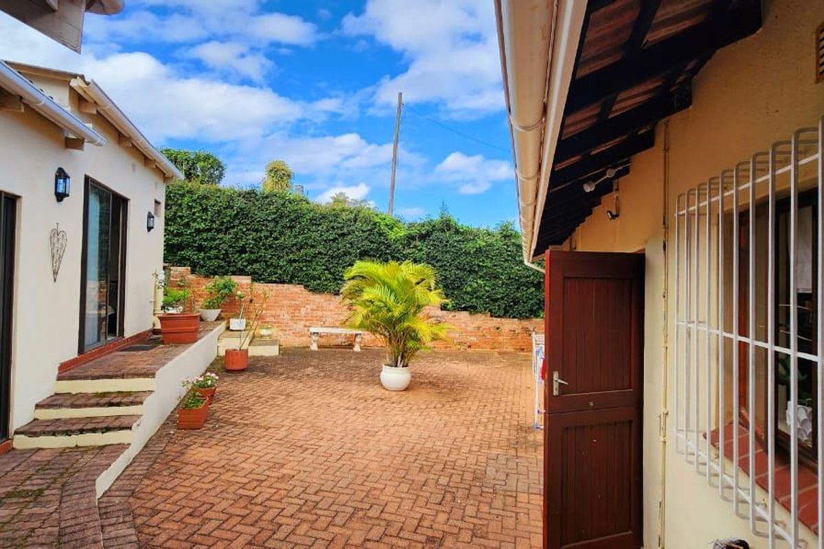 A private rear courtyard featuring brick paving, retaining walls, and direct access to the home via sliding glass doors.