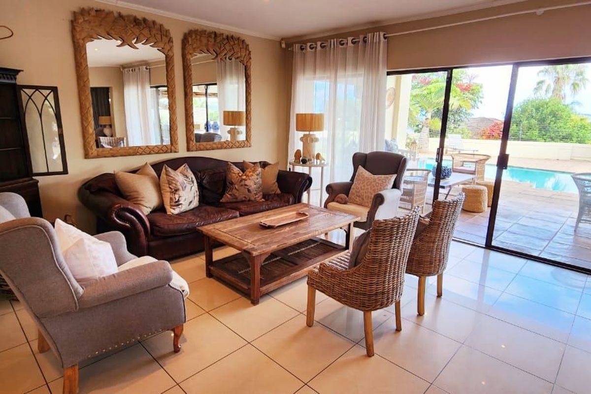 Spacious living room featuring tiled flooring and large sliding glass doors that provide seamless access to the outdoor patio and pool area.