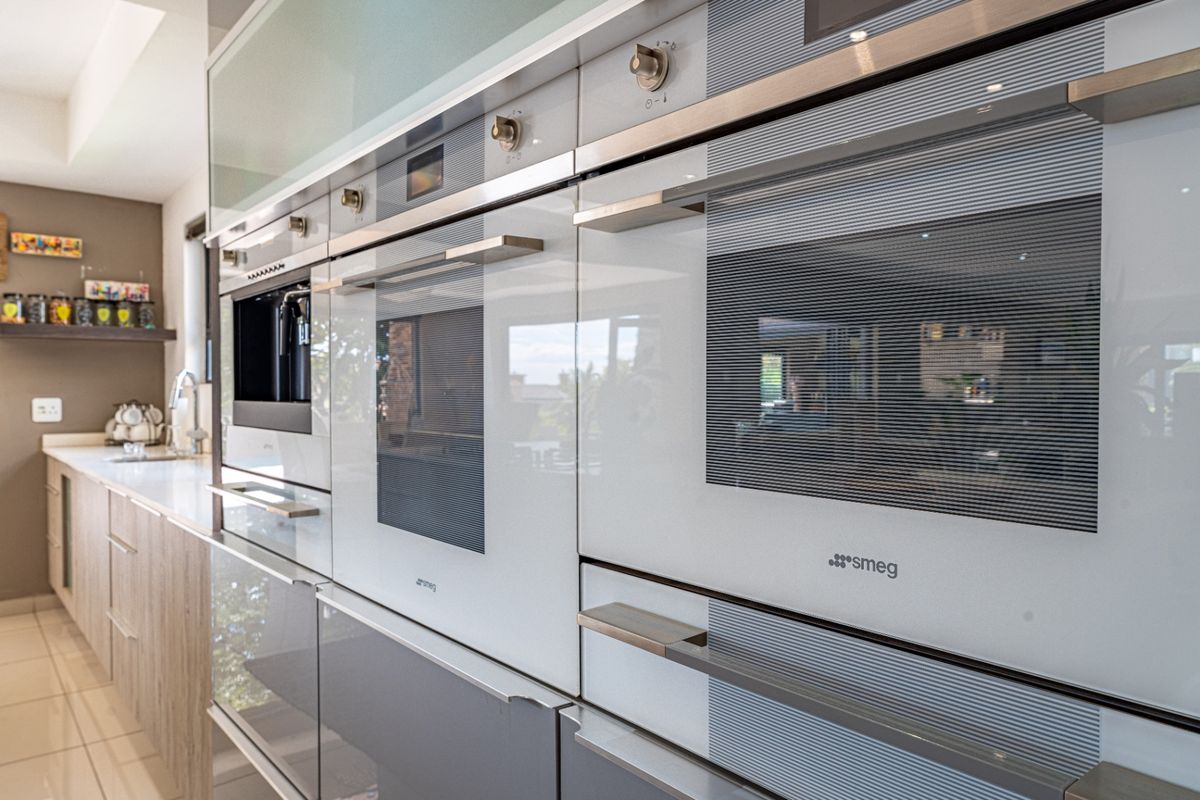 Modern kitchen featuring a sleek bank of integrated Smeg ovens and high-end cabinetry with clean lines and contemporary finishes.