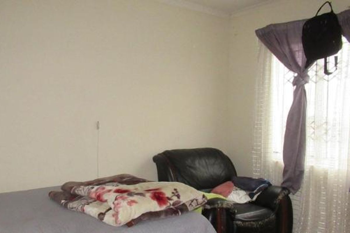 A standard bedroom featuring a built-in wardrobe and a window fitted with a security gate.