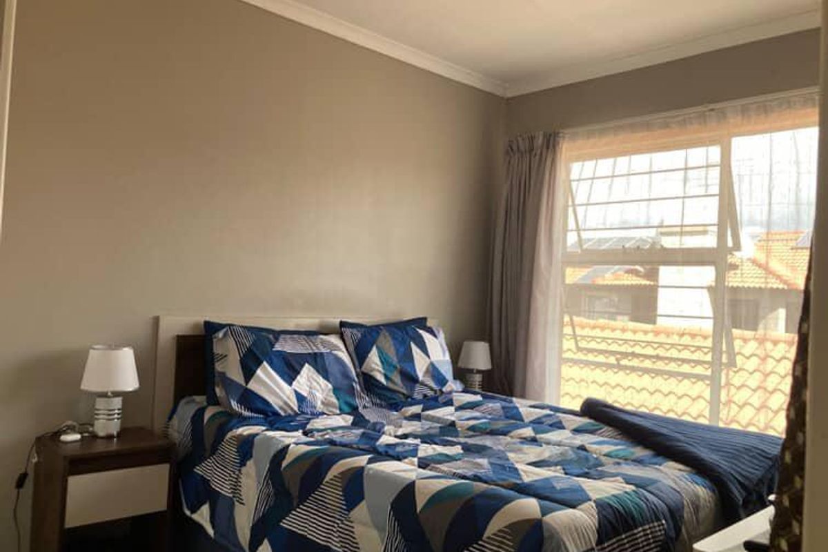 A functional bedroom featuring neutral wall tones, coving, and a large window fitted with security bars for added safety.