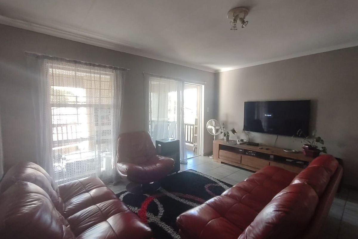 A comfortable living room featuring tiled flooring, coved ceilings, and direct access to an outdoor balcony through sliding glass doors.