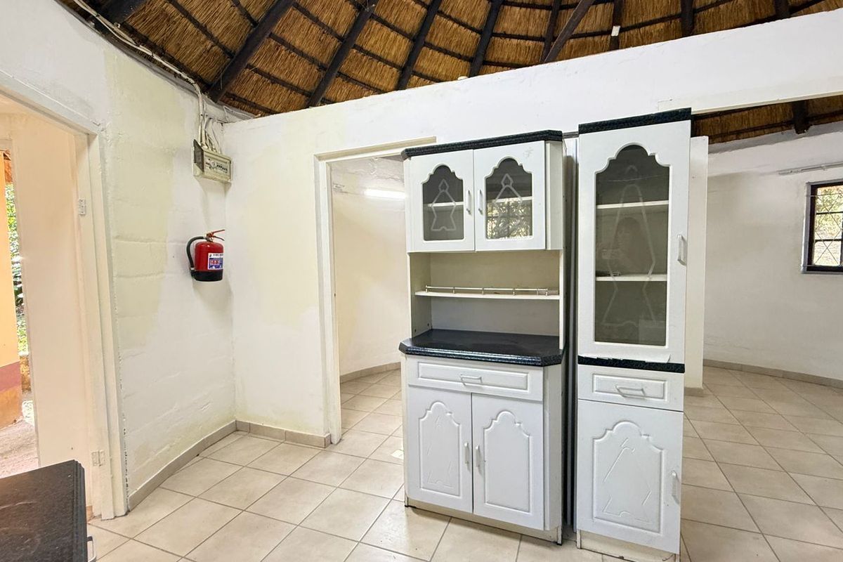 Living area featuring a traditional thatched roof, ceramic tiled flooring, and built-in cabinetry, requiring cosmetic updates to the wall finishes.