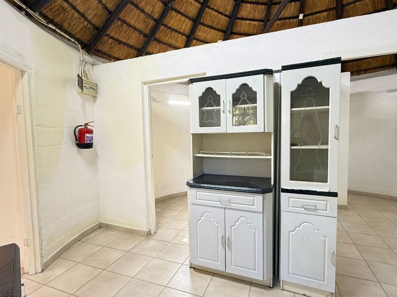 Living area featuring a traditional thatched roof, ceramic tiled flooring, and built-in cabinetry, requiring cosmetic updates to the wall finishes.