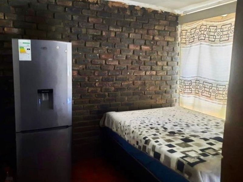 A bedroom featuring an exposed brick wall and basic finishes, requiring cosmetic updates to improve the overall aesthetic and living standard.