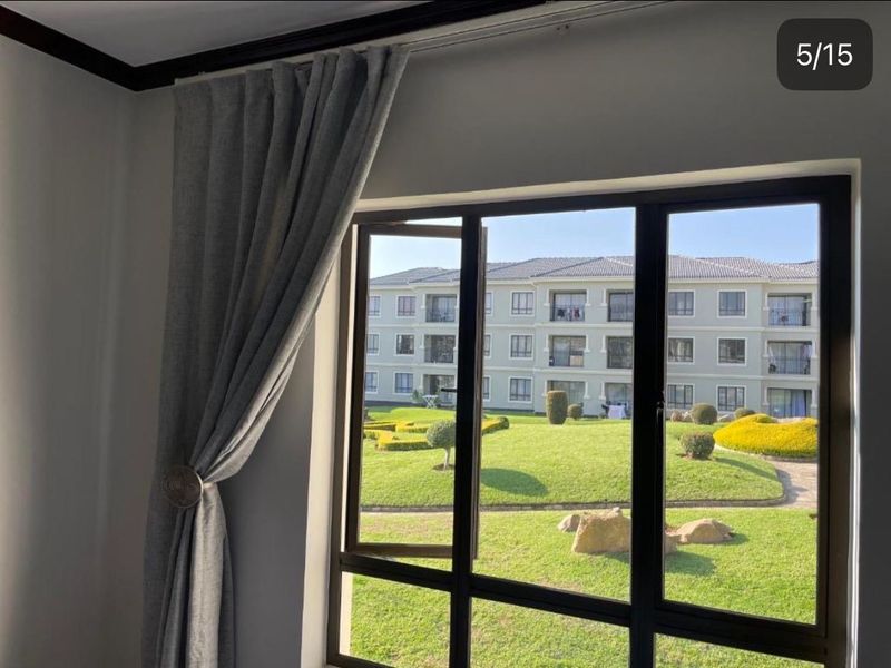 A view from an interior window looking out over a landscaped apartment complex garden and courtyard area.