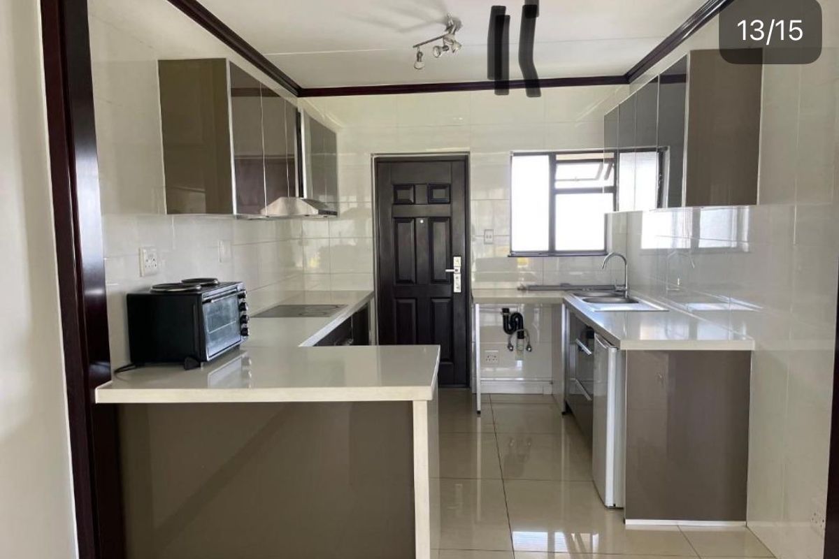 A modern kitchen featuring glossy cabinetry, stone countertops, and tiled finishes. The space is clean and functional, ready for final touches.