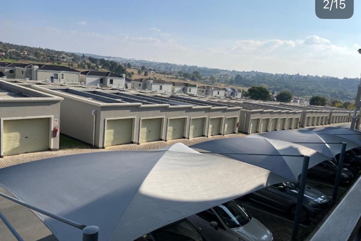An elevated view of a residential complex featuring a row of garages and covered parking bays with shade sails.