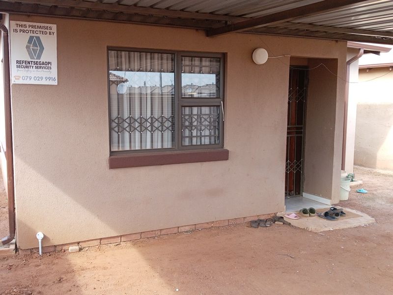 Front exterior view of the property featuring a covered carport, security gate, and burglar bars on the window.