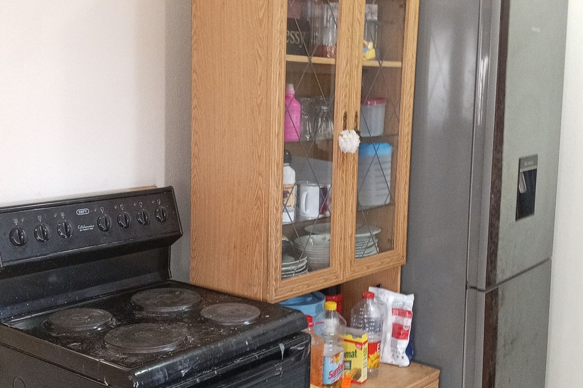 A functional kitchen area featuring a freestanding stove, built-in wooden cabinetry, and tiled flooring.