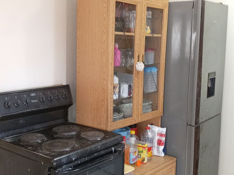 A functional kitchen area featuring a freestanding stove, built-in wooden cabinetry, and tiled flooring.