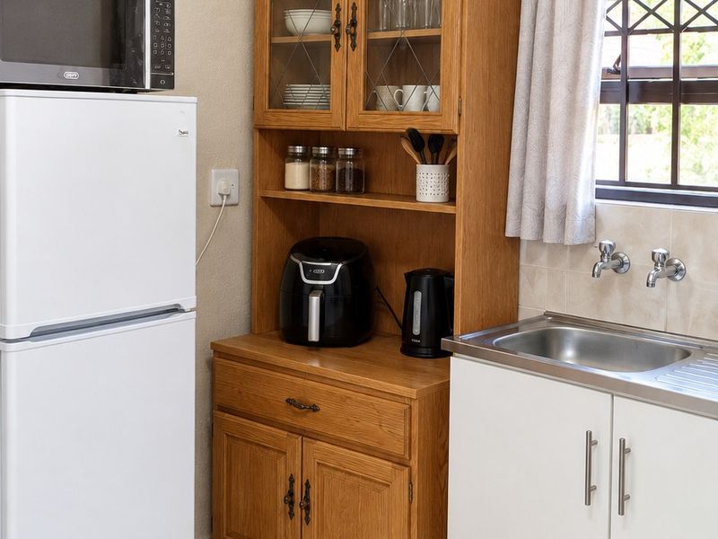 A functional kitchen area featuring tiled flooring, a stainless steel sink with chrome fixtures, and built-in cabinetry with a window providing natural light.