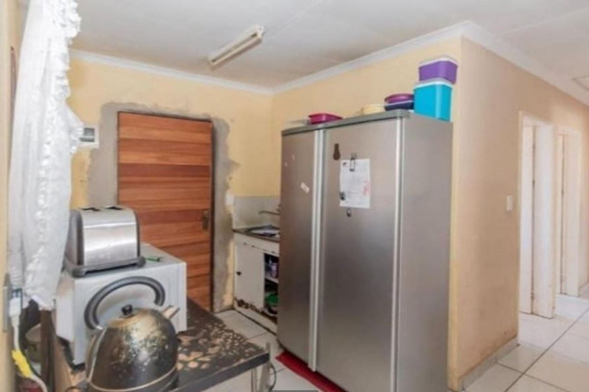 A dated kitchen area featuring tiled flooring and built-in cabinetry, currently requiring cosmetic updates and finishing work around the door frame.