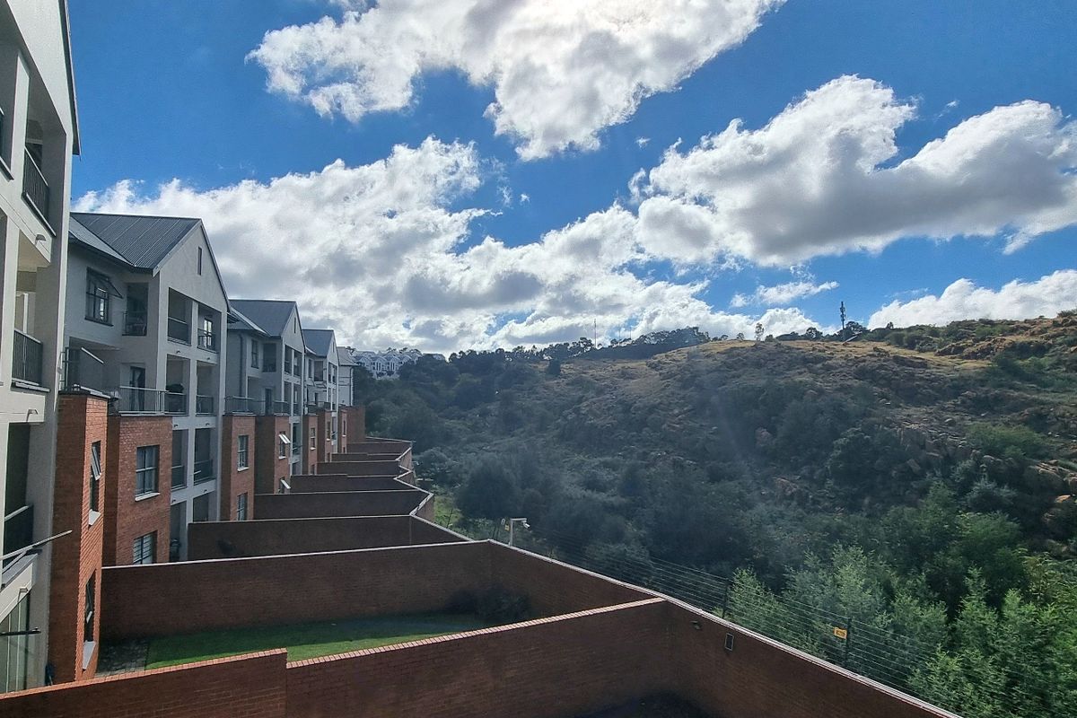 An elevated view of the apartment complex exterior, showcasing the brick facade, balconies, and the surrounding natural landscape.
