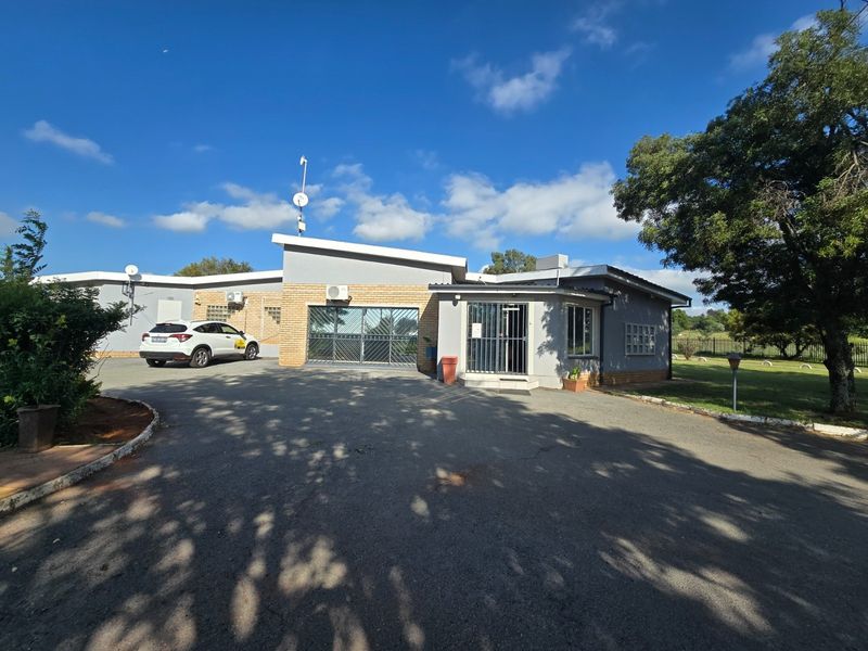 Front exterior view of the farm property featuring an asphalt driveway, brick facade, and secure entrance with security gates and bars.