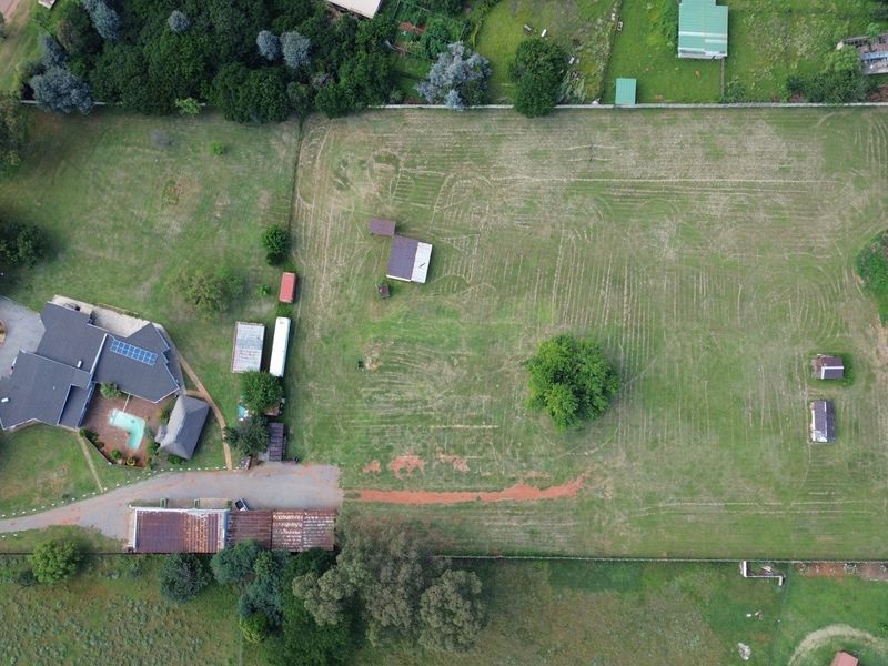 Aerial view of the farm property featuring the main residence with a swimming pool, multiple outbuildings, and expansive open land.