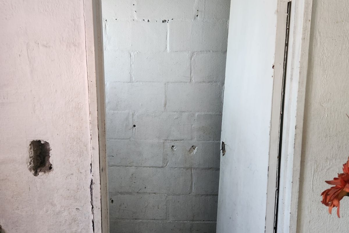 A small, unfinished bathroom space featuring exposed concrete block walls and tiled flooring, requiring significant cosmetic renovation and repair.