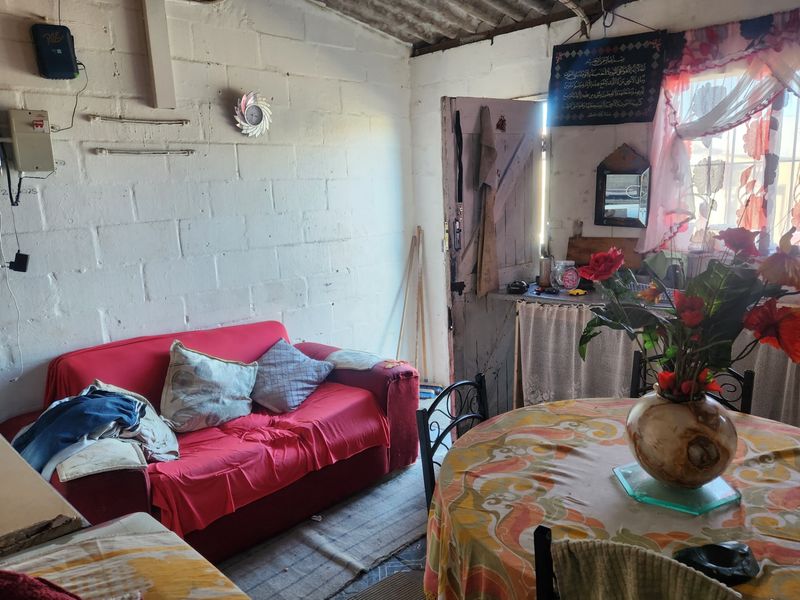 A living area featuring exposed corrugated roof sheeting and painted concrete block walls, offering a rustic, unfinished aesthetic.