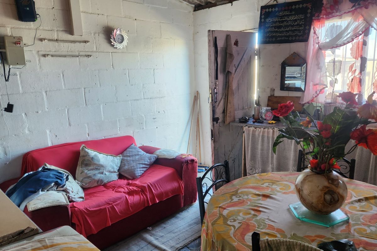 A living area featuring exposed corrugated roof sheeting and painted concrete block walls, offering a rustic, unfinished aesthetic.