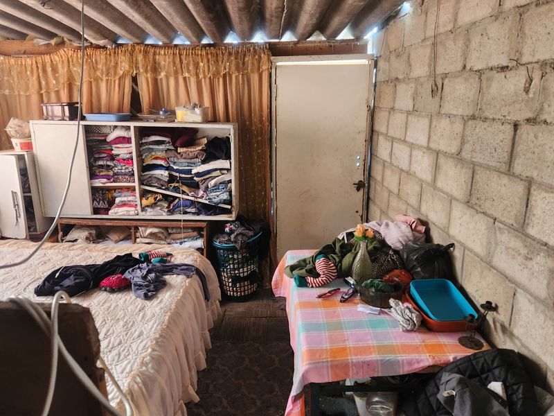 A bedroom featuring exposed concrete block walls and corrugated roofing, offering a rustic, unfinished aesthetic that could be enhanced with renovation.