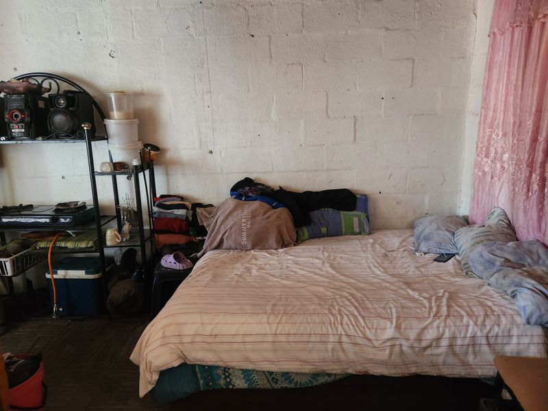 A bedroom featuring exposed concrete block walls and basic flooring, offering a blank canvas for renovation and interior finishing.