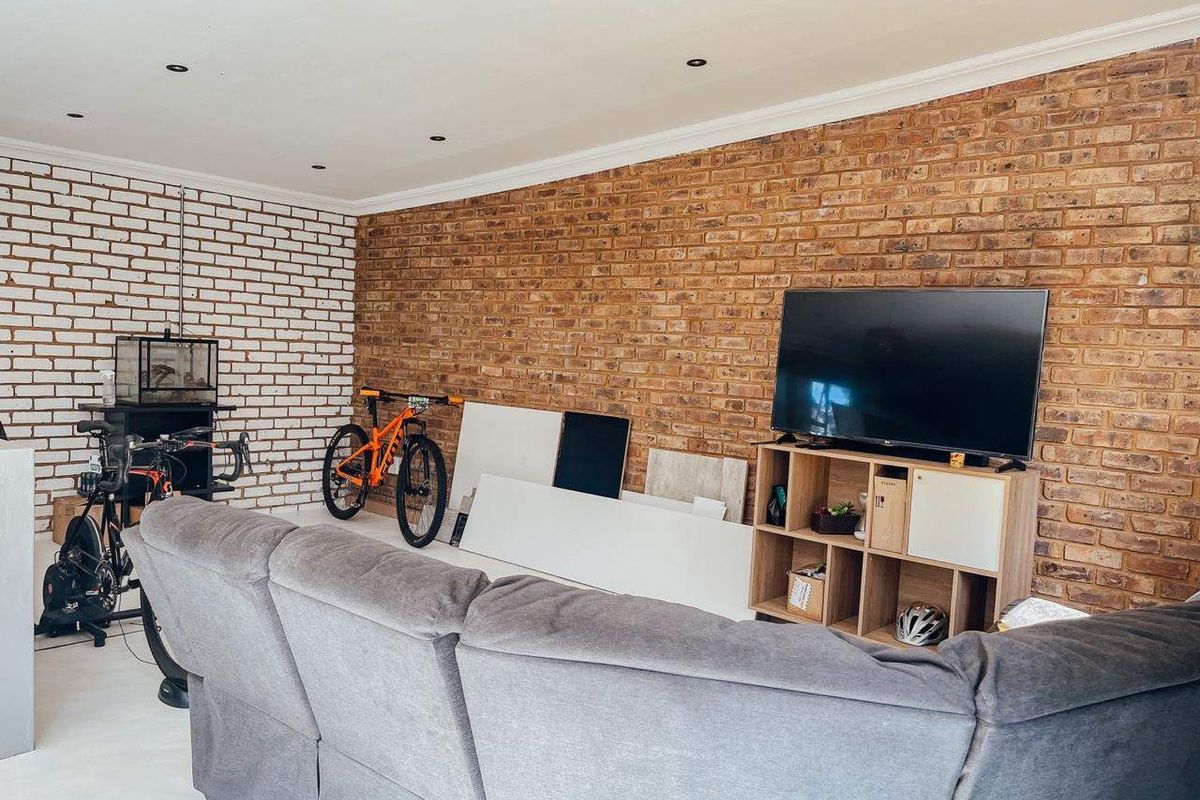 Living room featuring a prominent exposed brick feature wall, painted brick accents, and recessed downlighting.