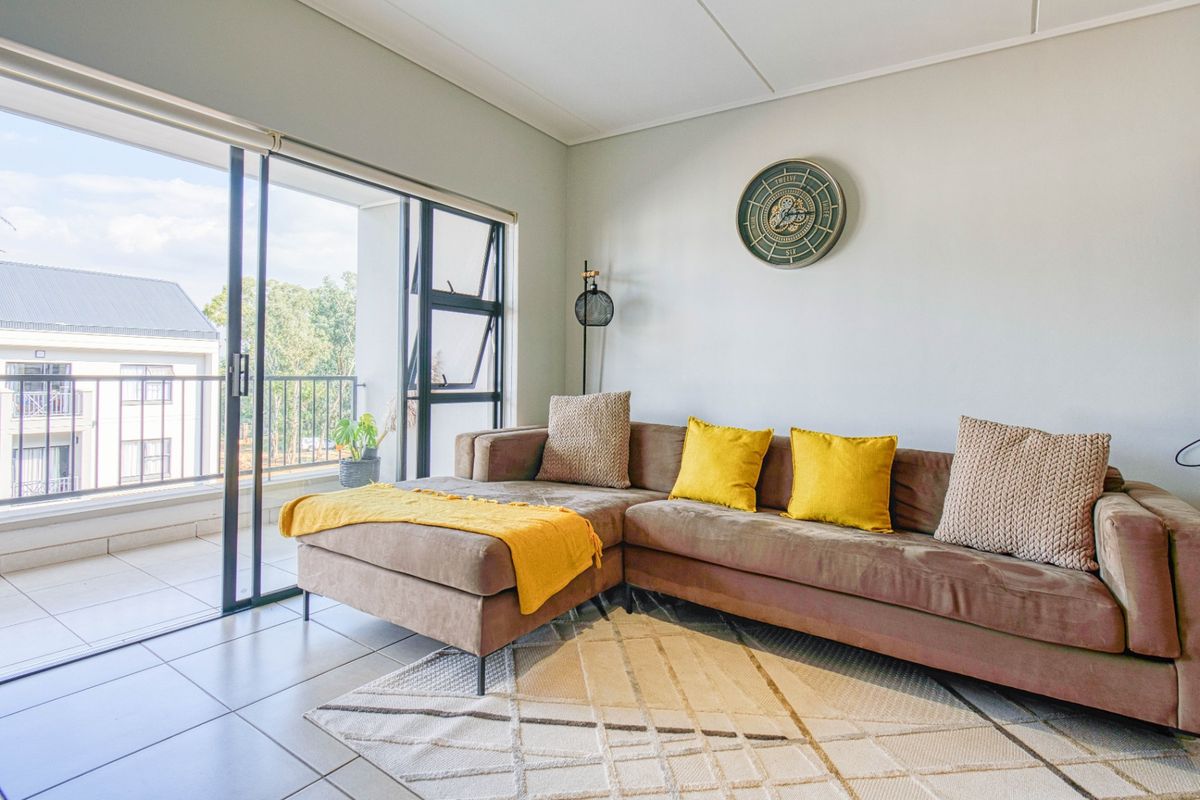 Bright living room featuring large sliding glass doors that open onto a private balcony, finished with neutral floor tiles and clean wall finishes.