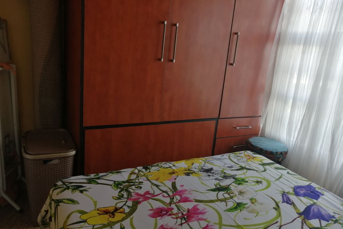 A bedroom featuring a large, wood-finish built-in wardrobe providing ample storage space.