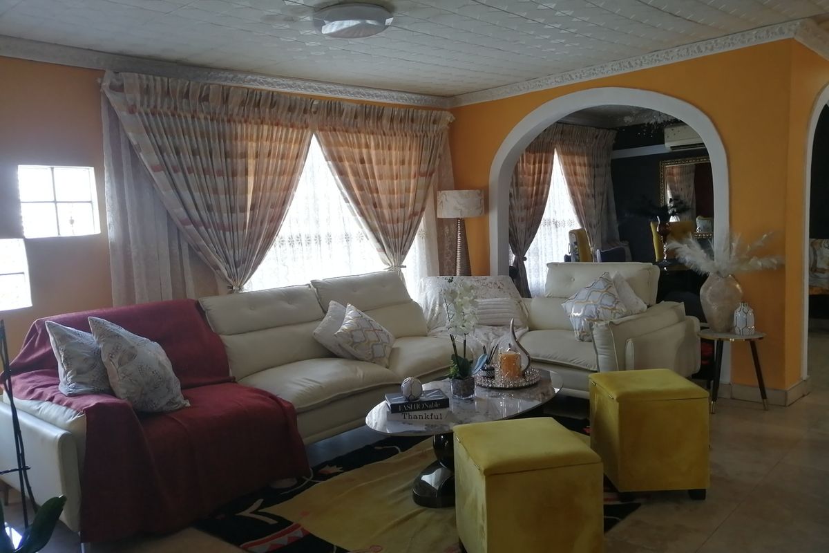 A spacious living room featuring tiled flooring, decorative ceiling tiles, and a distinctive arched entryway leading to an adjacent space.