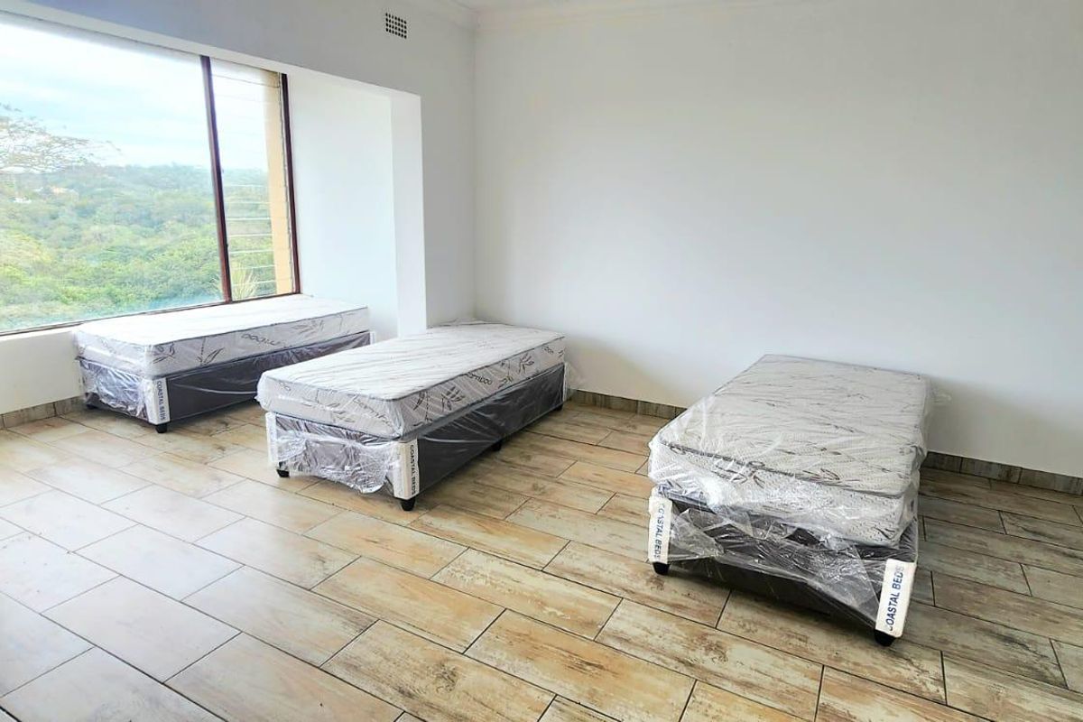 A spacious bedroom featuring large windows with scenic views and durable tiled flooring, providing a bright and neutral canvas for interior design.